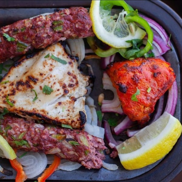 Bombay Palace's Indian mixed grill platter with seekh kebab, chicken tikka, naan, onions, and lemon.