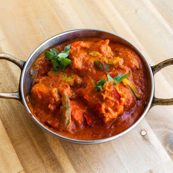 Bombay Palace's chicken tikka masala, garnished with cilantro, in a traditional metal karahi.